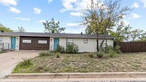 A single-story house with a garage, a front yard with sparse grass and shrubs, and a wooden fence in the background. - Stylish 3-Bedroom Austin Home in a Seriously Convenient Location (Austin)