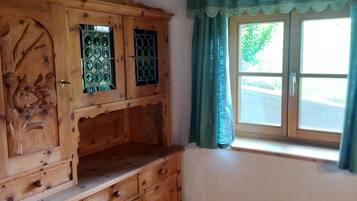 Ein Holzkabinett mit aufwendigen Schnitzereien, ein Fenster mit grünem Vorhang und ein Holzboden.