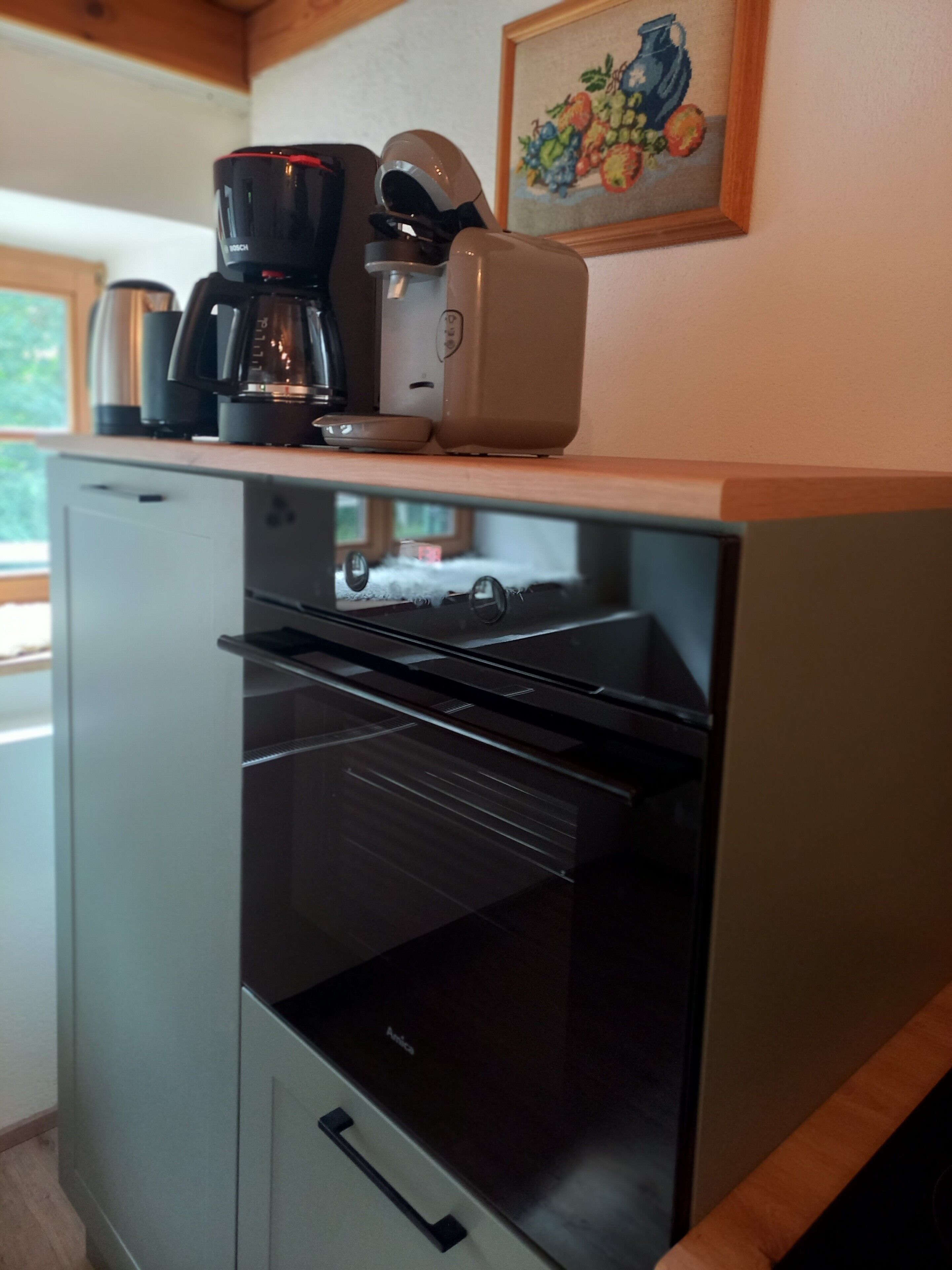 Eine kleine Küchenzeile mit Kaffeemaschine, Toaster und Backofen.