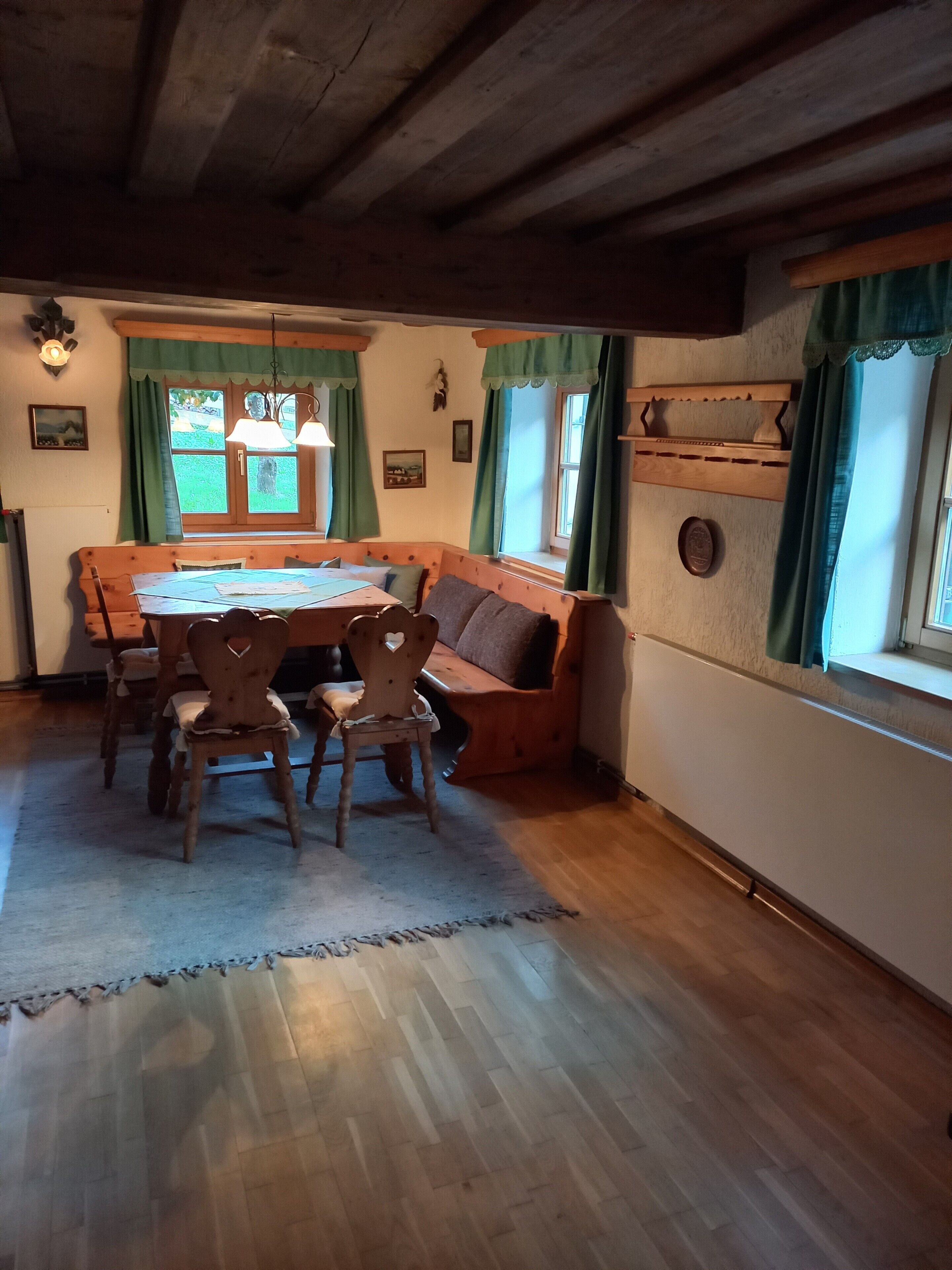 Een rustieke eethoek met een houten tafel, stoelen en een bank.