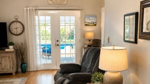 A living room with a dark leather sofa, a wooden side table with a lamp, a clock, and a sign above the door. - Netsled in  Navarre (Navarre)