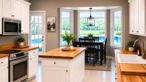A kitchen with white cabinetry, a wooden countertop, a built-in oven, and a dining area with a view of greenery. - Netsled in  Navarre (Navarre)