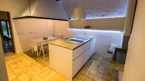 Cocina moderna con una isla central, muebles blancos y un comedor con mesa y sillas.