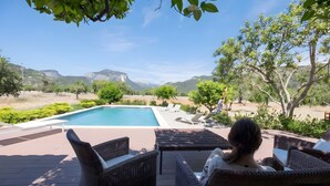 Zona de piscina con sillones de descanso, vista a montañas y cielo despejado.