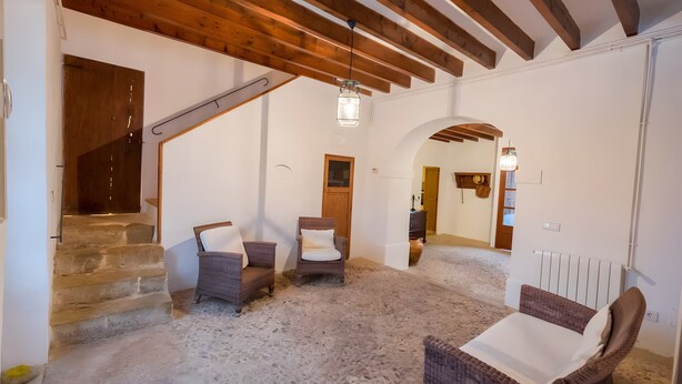 Una habitación con escaleras de piedra, muebles de mimbre y techo de madera.