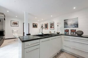 A modern kitchen with white cabinetry, a black countertop, and a stainless steel range hood. - 61-square-meter apartment with an 85-square-meter terrace and direct access to the pool. Hossegor Lake (Soorts-Hossegor)