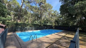 A rectangular swimming pool with a metal ladder, surrounded by a wooden deck and a metal fence. - 61-square-meter apartment with an 85-square-meter terrace and direct access to the pool. Hossegor Lake (Soorts-Hossegor)