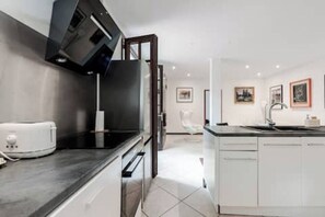 A modern kitchen with a black countertop, white cabinets, and a built-in dishwasher. - 61-square-meter apartment with an 85-square-meter terrace and direct access to the pool. Hossegor Lake (Soorts-Hossegor)
