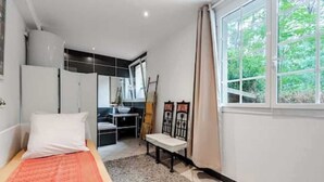 Ein Schlafzimmer mit Bett, Schreibtisch und einem Fenster mit Blick auf Grünflächen.