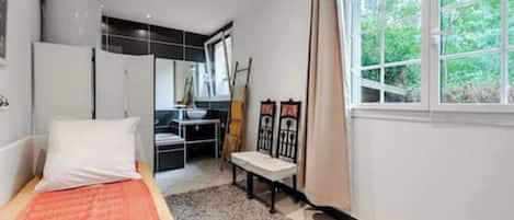 Ein Schlafzimmer mit Bett, Schreibtisch und einem Fenster mit Blick auf Grünflächen.