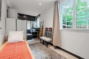 A bedroom with a bed, a desk, and a window with a view of greenery. - 61-square-meter apartment with an 85-square-meter terrace and direct access to the pool. Hossegor Lake (Soorts-Hossegor)