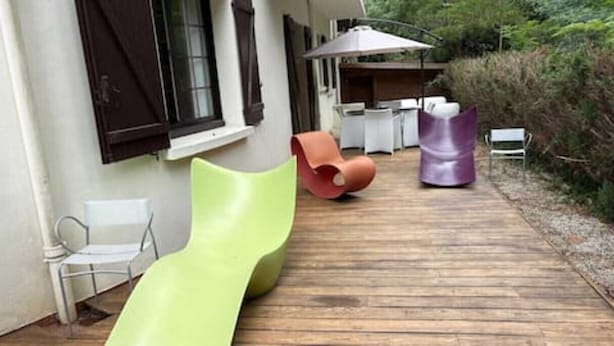 Eine Holzterrasse mit Gartenmöbeln, darunter Stühle und ein Tisch.