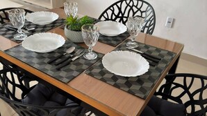 Une table à manger dressée avec des assiettes, des verres et des couverts, entourée de chaises.