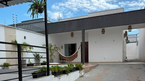 Un espace extérieur abrité, doté d’un hamac, de plantes en pot et d’un sol en béton.