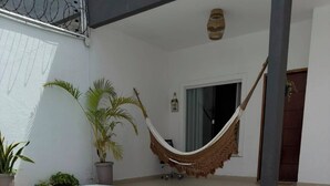 Une piscine avec une terrasse en bois, un hamac et des plantes en pot.