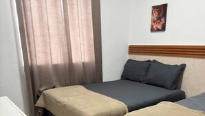 Une chambre avec deux lits, une petite table et un tableau accroché au mur.