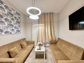 A modern living room with two sofas, a coffee table, and a wall-mounted TV. - Cozy Studio beautiful London perfect for your stay (London)