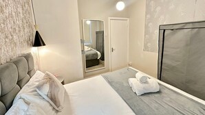Een hotelkamer met een bed, nachtkastje, spiegel, kast en raam.