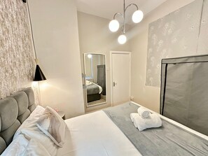 A hotel room with a bed, a bedside table, a mirror, a wardrobe, and a window. - Cozy Studio beautiful London perfect for your stay (London)