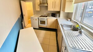 Een kleine keuken met een fornuis, oven, magnetron en spoelbak.