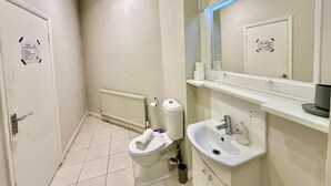 Een badkamer met toilet, wastafel, spiegel en een witte deur.