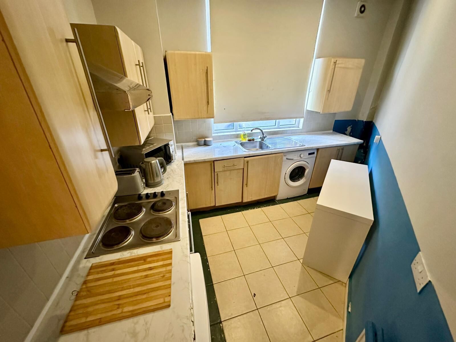 A compact kitchen with a stove, microwave, sink, and washing machine.