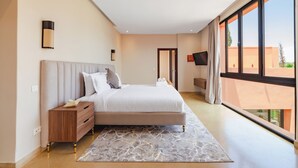 Una camera da letto moderna con un letto grande, un comodino, una TV a schermo piatto e vista all'esterno.