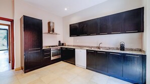 Una cucina moderna con mobili scuri, una cappa aspirante in acciaio inossidabile e un piano di lavoro in granito.