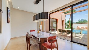 Un'area pranzo moderna con un tavolo grande, sedie e una lampada a sospensione.