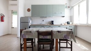 A kitchen with light green cabinets, a refrigerator, a coffee maker, and a dining table with chairs. - Lilli's House (Ponte Buggianese)
