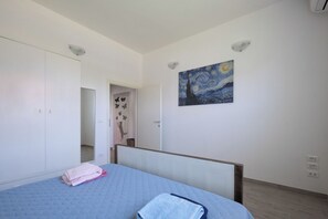 Ein Schlafzimmer mit einem Bett, einer Tür, einem Gemälde und einer Lampe.