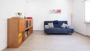 A room with a blue sofa, a wooden bookshelf, and a painting on the wall. - Lilli's House (Ponte Buggianese)