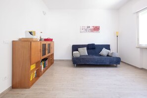 Ein Zimmer mit einem blauen Sofa, einem Holzregal und einem Gemälde an der Wand.