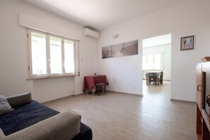 Ein geräumiger Wohnbereich mit einer Couch, einem Esstisch mit Stühlen und einer Küchenzeile mit Schränken.