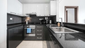 Una cucina moderna con piani di lavoro neri, elettrodomestici in acciaio inossidabile e un lavello a due vasche.