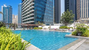 Una piscina con lettini e vista su edifici moderni.
