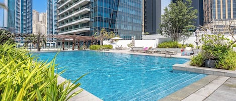 A swimming pool with lounge chairs and a view of high-rise buildings.