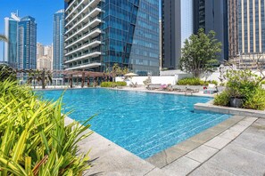 Ein Pool mit Liegestühlen und Blick auf hohe Gebäude.