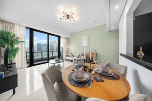 A modern dining area with a round table set for four, a sofa, and a city view through large windows.