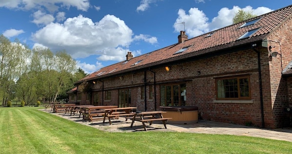 A brick building with a tiled roof, outdoor seating, and a well-maintained lawn.