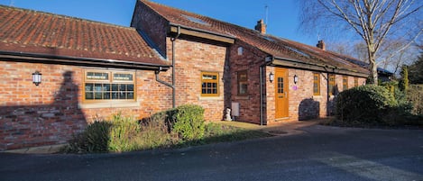 A brick building with a tiled roof, a front door, and a window.