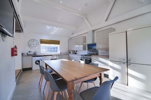 A modern kitchen with a dining table, chairs, and a large refrigerator.