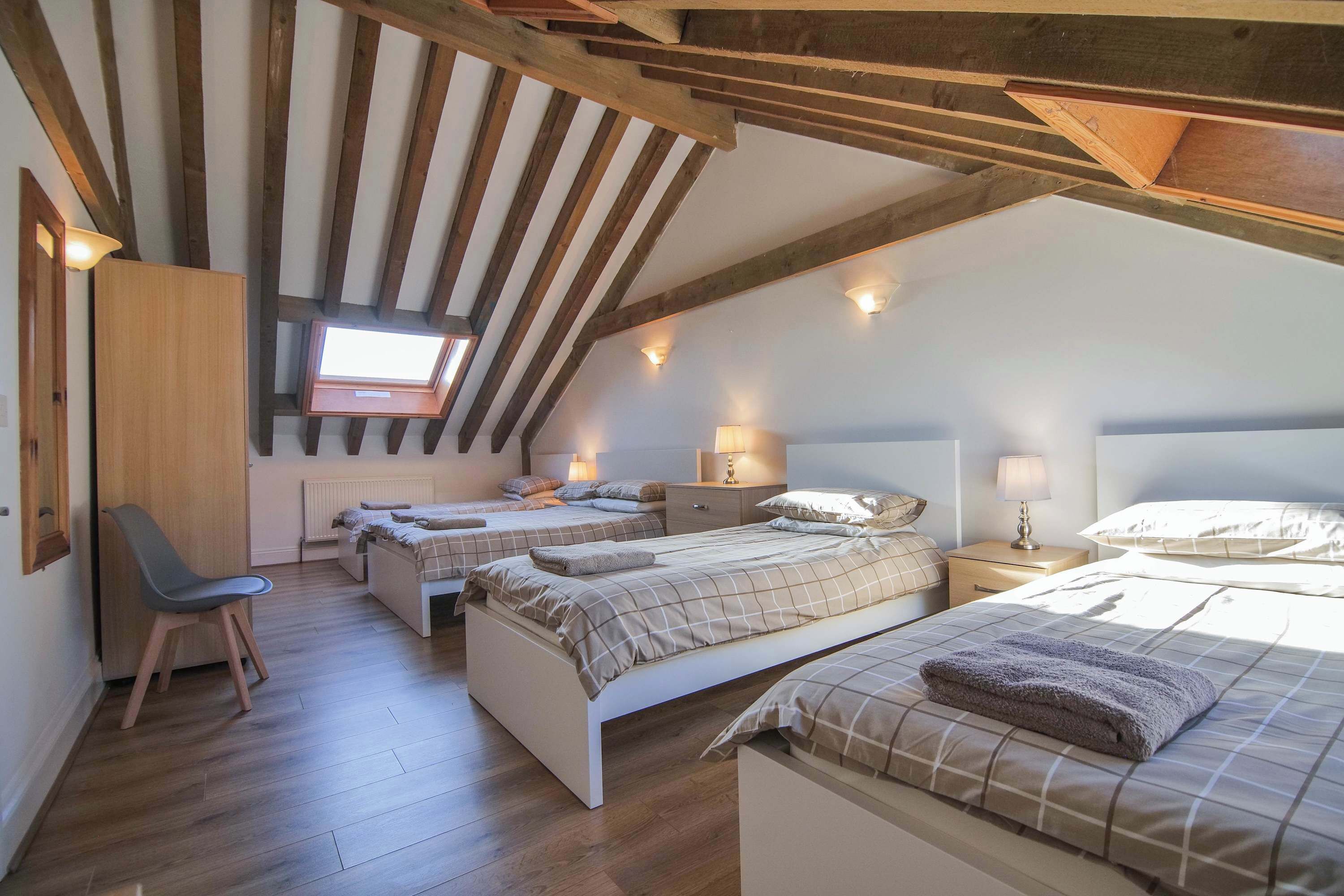 A bedroom with two beds, a desk, and a chair.
