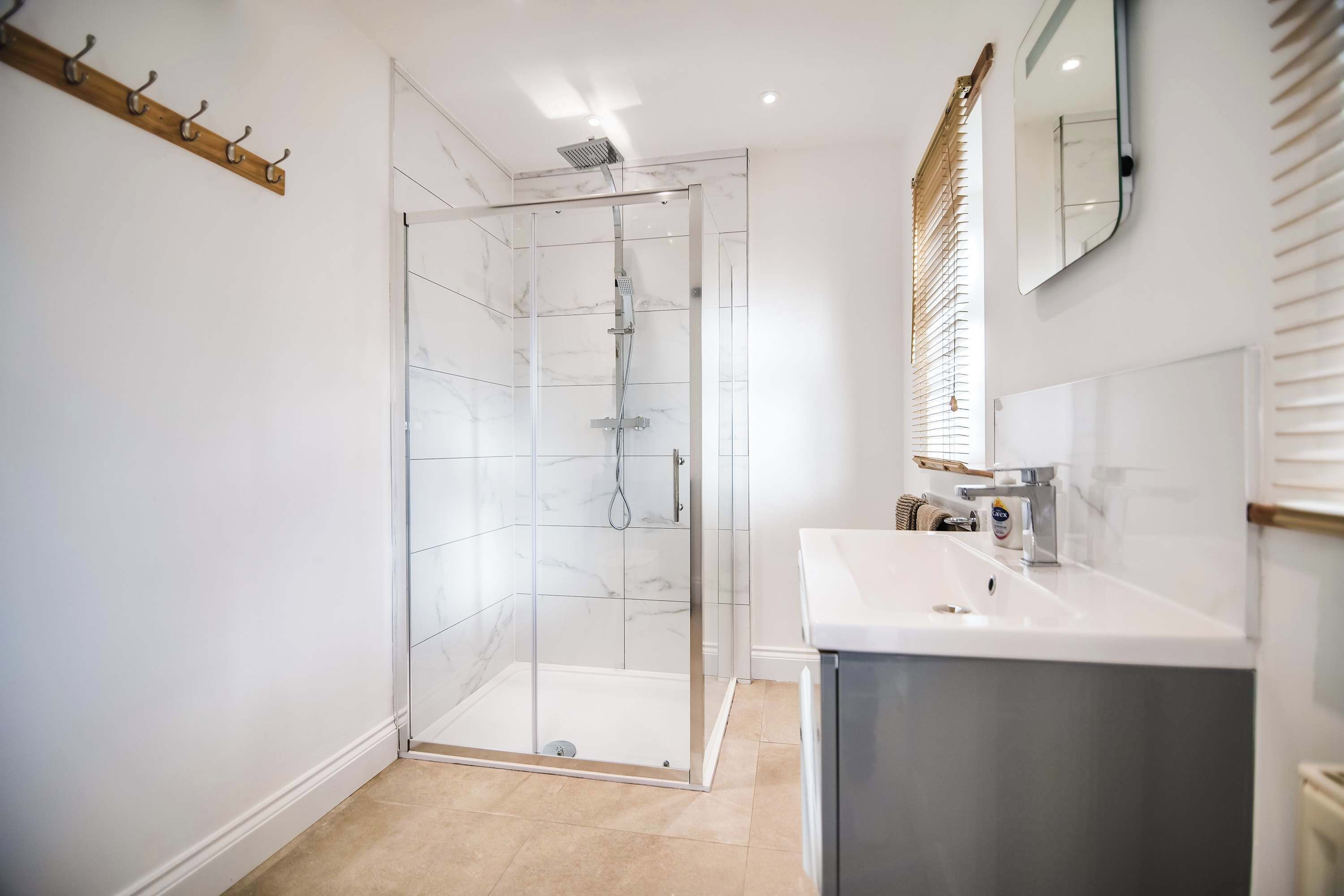 Une salle de bain moderne avec une douche à parois de verre, un lavabo blanc et un miroir.