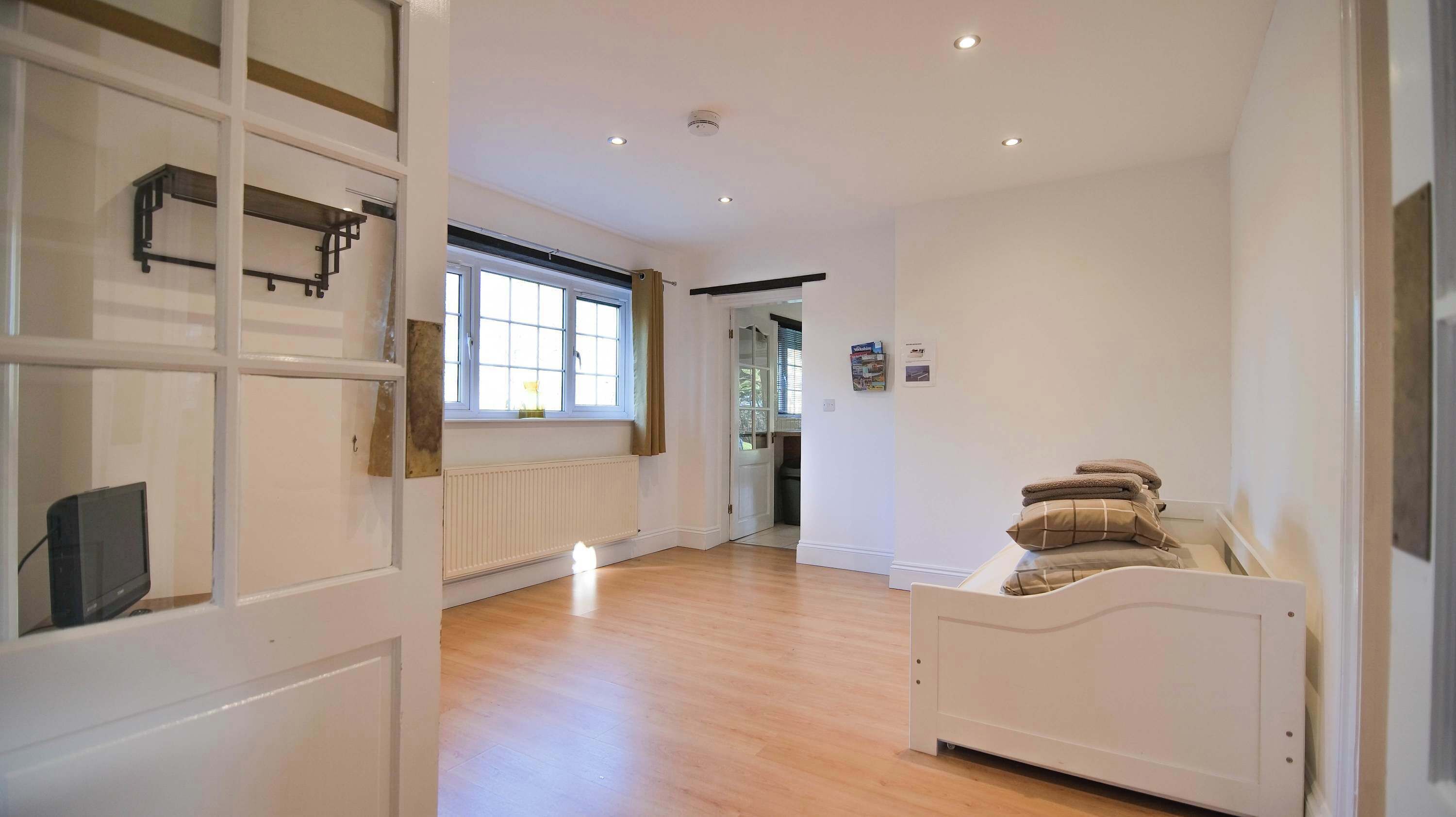 A room with a bed, a radiator, a window, and a door leading to another room.