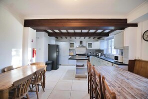 Una cocina moderna con una isla central, armarios blancos y una mesa de comedor de madera con sillas.