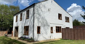 Una casa blanca de dos pisos con numerosas ventanas y entrada de ladrillo.