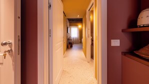 A hallway with doors leading to a bathroom and a kitchen area. - Spaccavento Boutique Rooms (Chioggia)