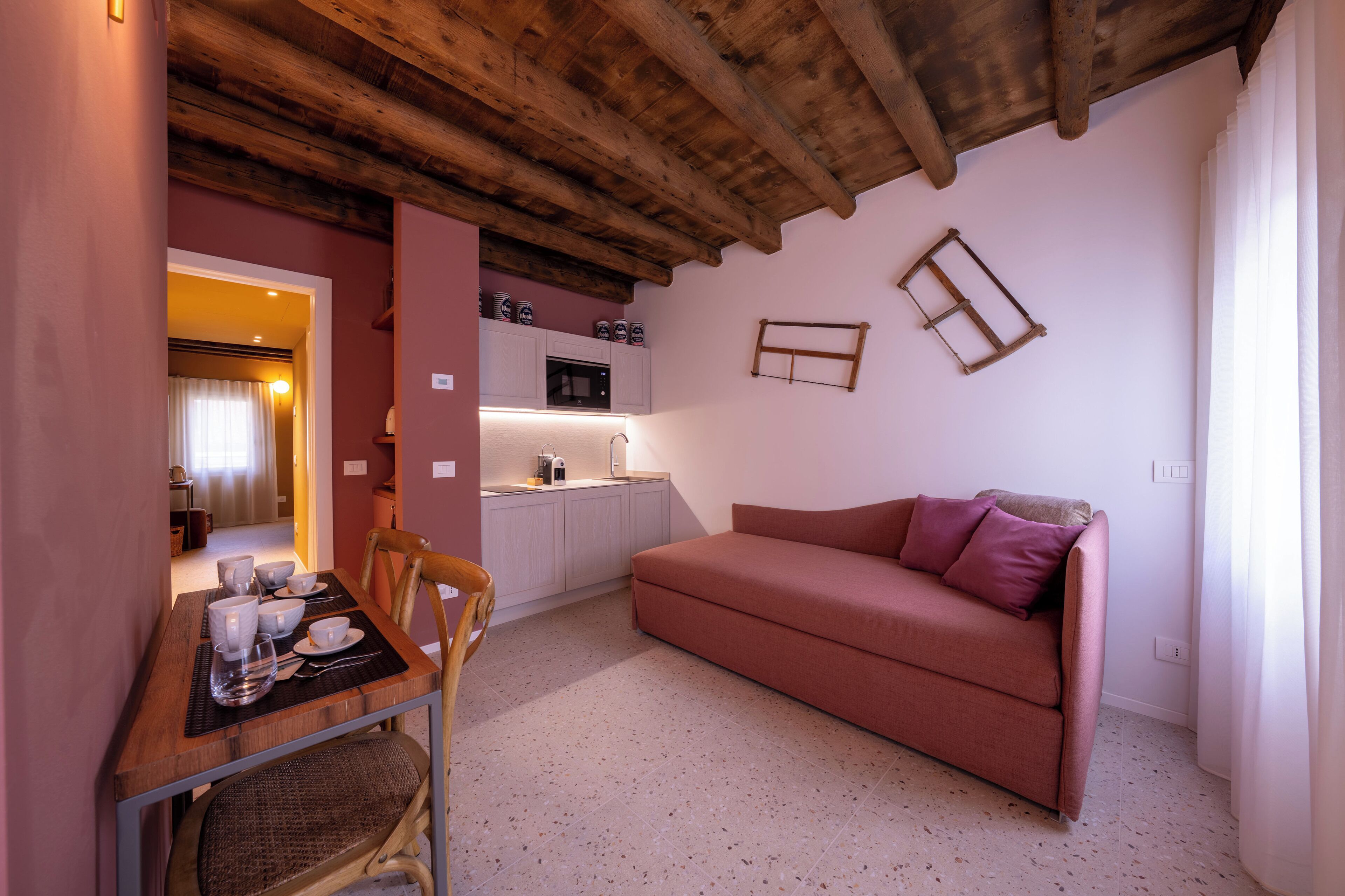A compact living space with a kitchenette, a dining area with a table and chairs, and a sofa with cushions.