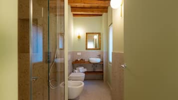 Un baño con cabina de ducha de vidrio, un lavamanos, inodoro y un espejo en la pared.
